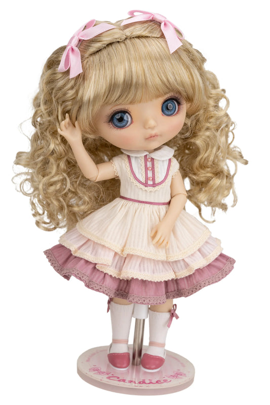 Candice doll with blonde hair, blue eyes, and a pink and white dress on a white background