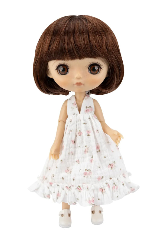A doll with brown hair and large eyes wearing a white sleeveless dress with a pink floral pattern and white shoes, isolated on a white background.