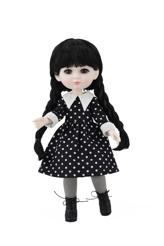 Doll with black hair styled in pigtails, wearing a black and white polka dot dress on a white background.