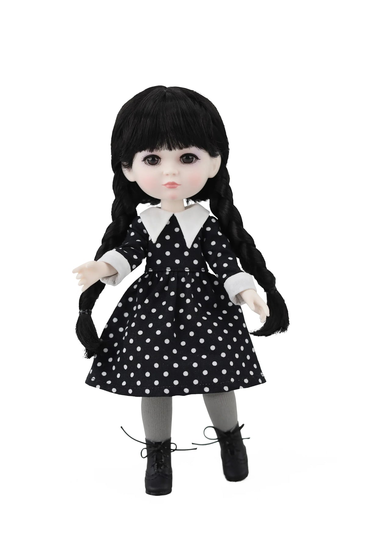 Doll with black hair styled in pigtails, wearing a black and white polka dot dress on a white background.