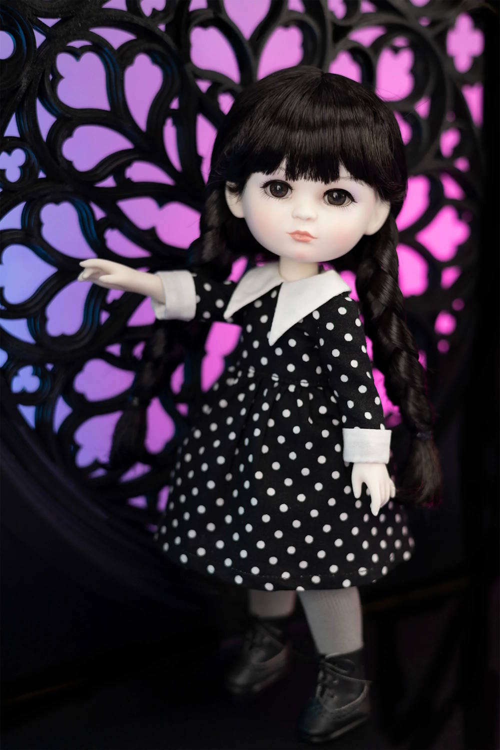 Doll wearing a black and white polka dot dress with a decorative background