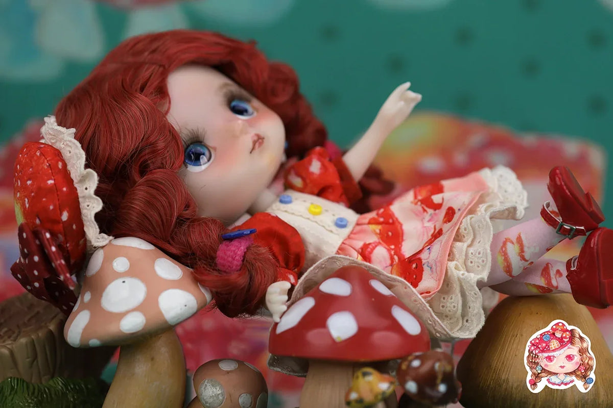 Mori Lolli Doll with red hair and a colorful outfit sitting on mushroom-shaped objects with a blurred background.
