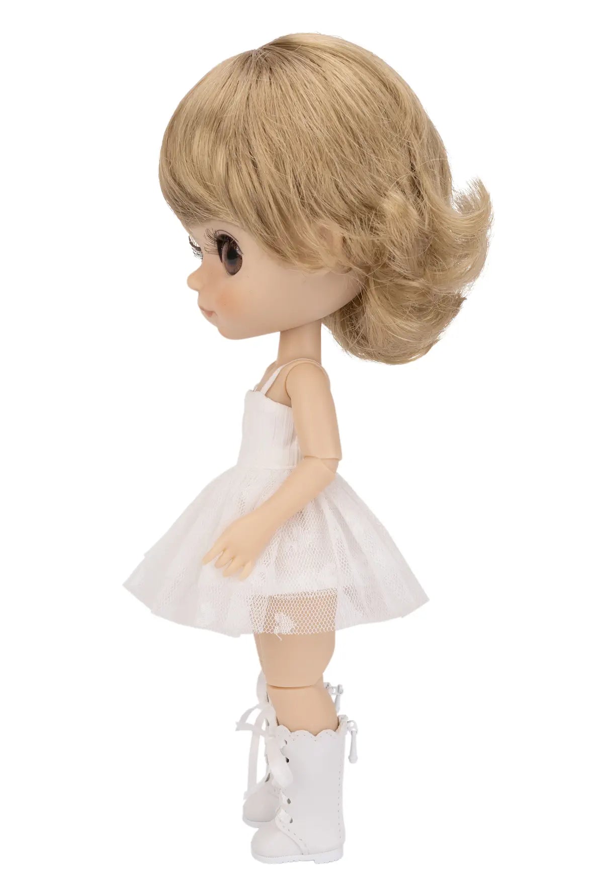A doll with blonde hair, wearing a white sleeveless dress and white lace-up boots, shown against a plain white background.