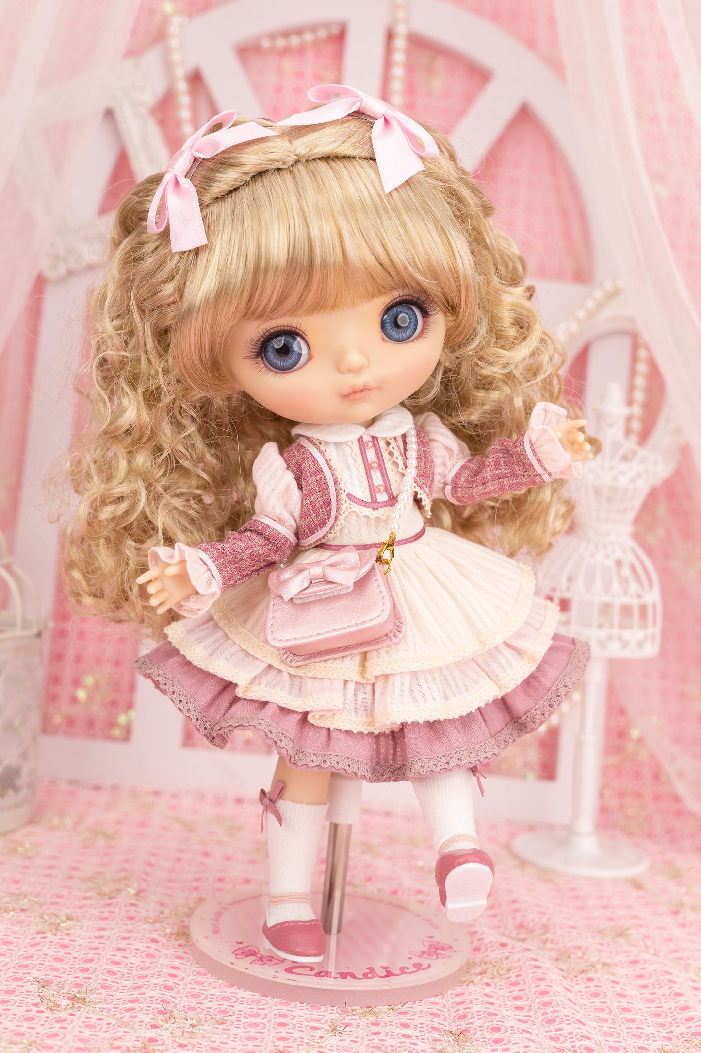 Candice doll with blonde hair and blue eyes in a pink outfit on a pink background