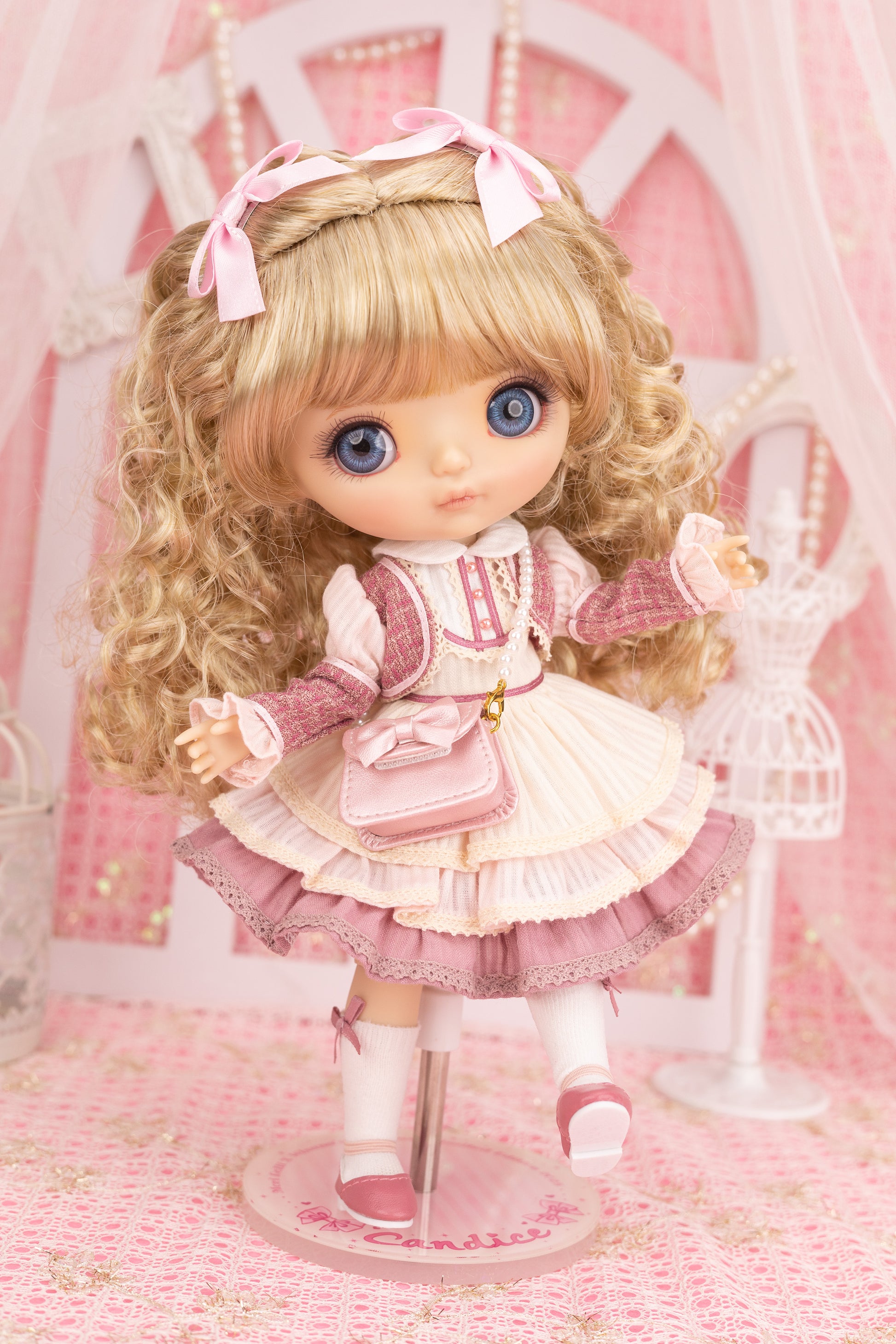 Candice doll with blonde hair and blue eyes in a pink outfit on a pink background