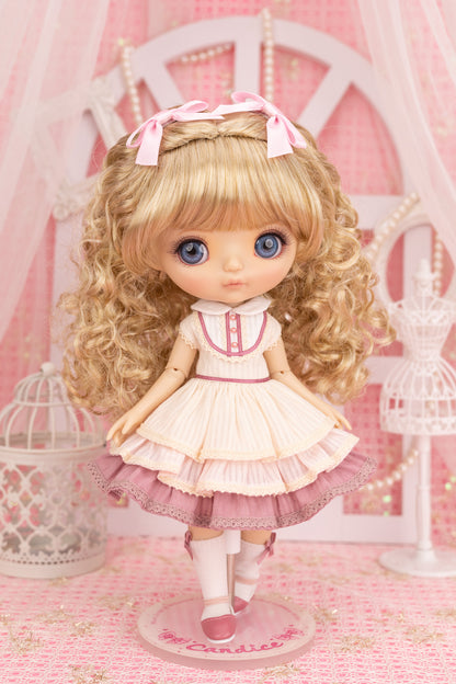 Candice doll with blonde hair and a pink dress in a decorative setting