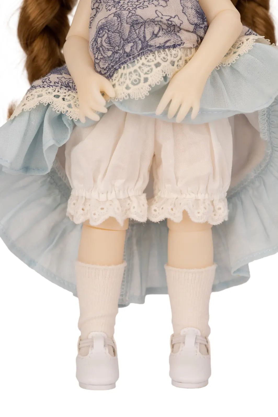 Doll wearing a light blue dress with lace details on a white background
