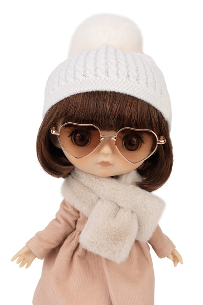 Doll wearing a white knit hat, brown sunglasses, and a beige coat with a fur scarf on a white background