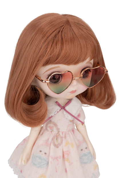 Doll with heart-shaped sunglasses with pink and green gradient lenses and a floral dress on a white background