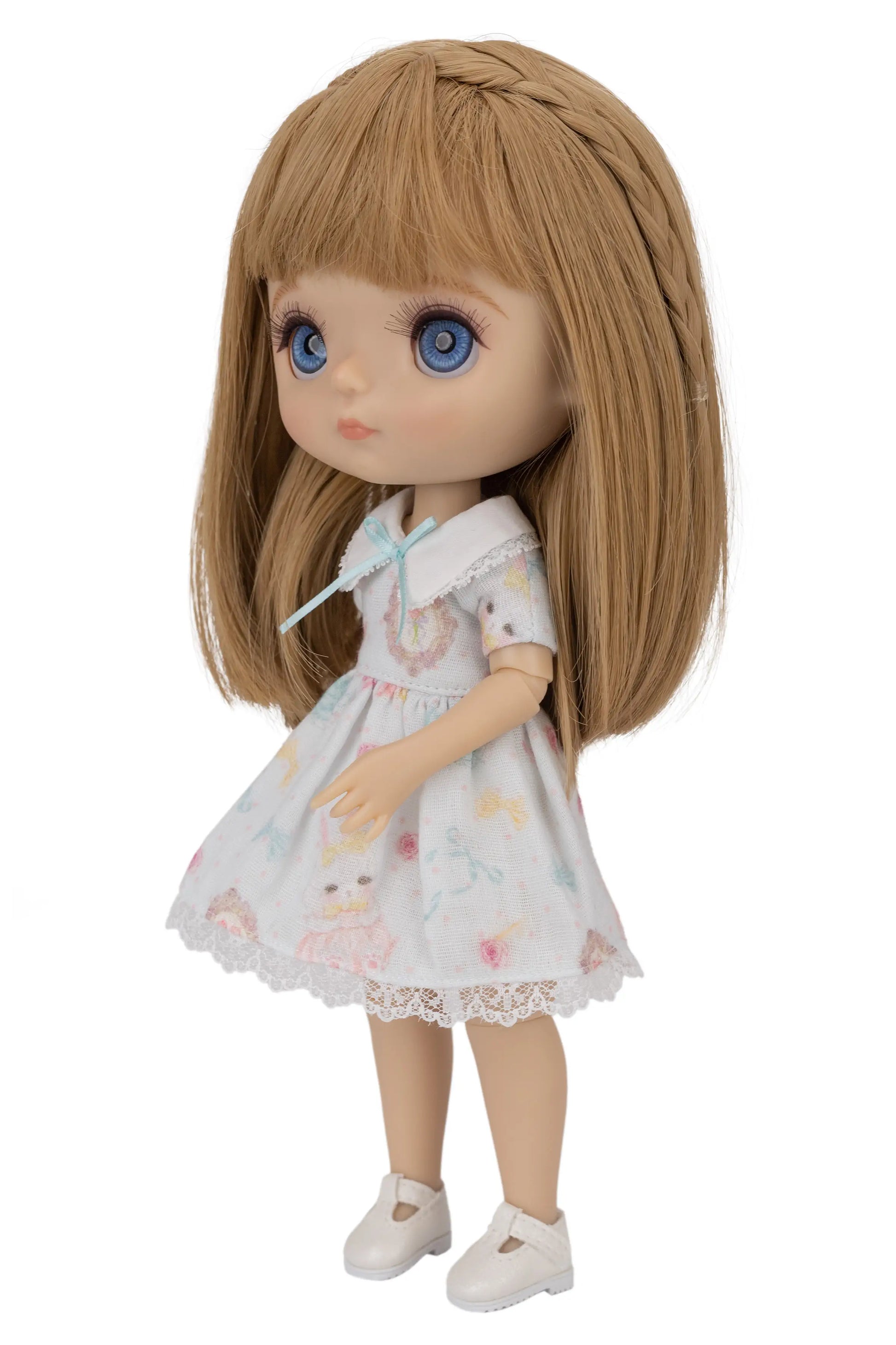 Doll with long brown hair wearing a white dress with floral patterns on a white background
