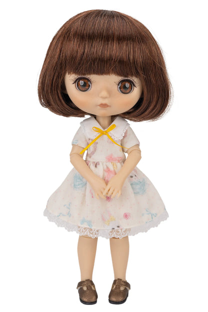 Doll with brown hair and a white dress with colorful patterns on a white background
