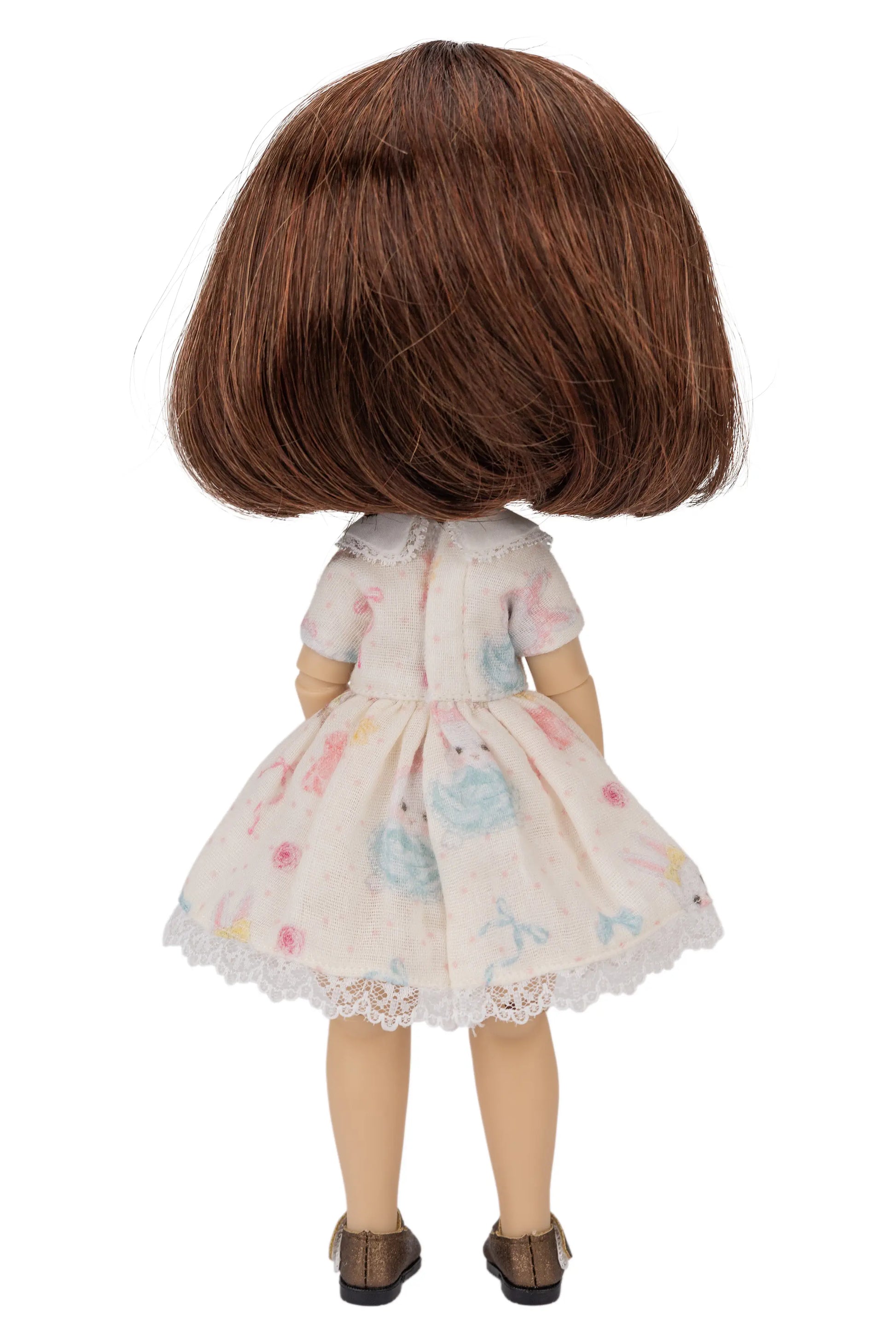 Doll with brown hair wearing a floral dress on a white background
