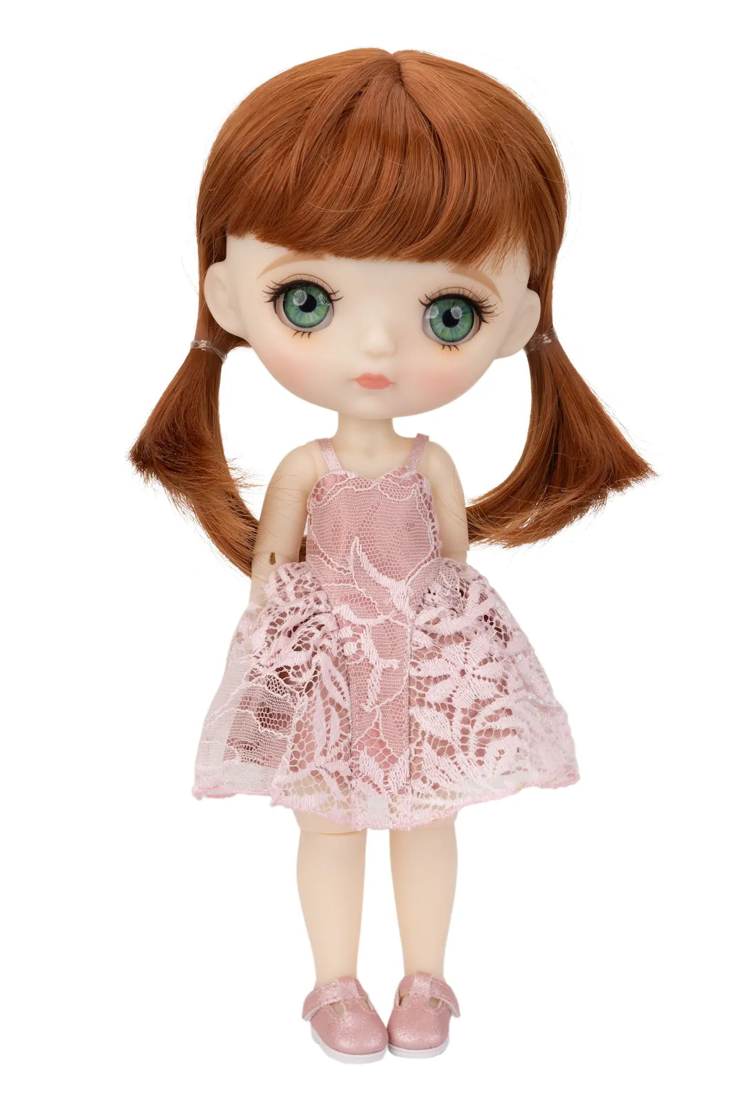 A Mori Lolli doll with large green eyes, reddish-brown hair in pigtails, and a light pink lace dress with matching pink shoes, shown against a plain white background.