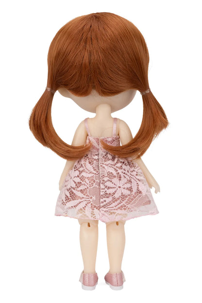 Back view of a doll with long auburn hair in pigtails, wearing a light pink lace dress and pink shoes, isolated on a white background.