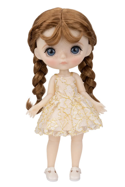 A doll with large blue eyes, long auburn hair in two braids, and a cream-colored dress with a gold floral pattern, standing against a plain white background.