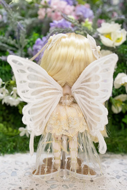Doll with butterfly wings and blonde hair against a floral background