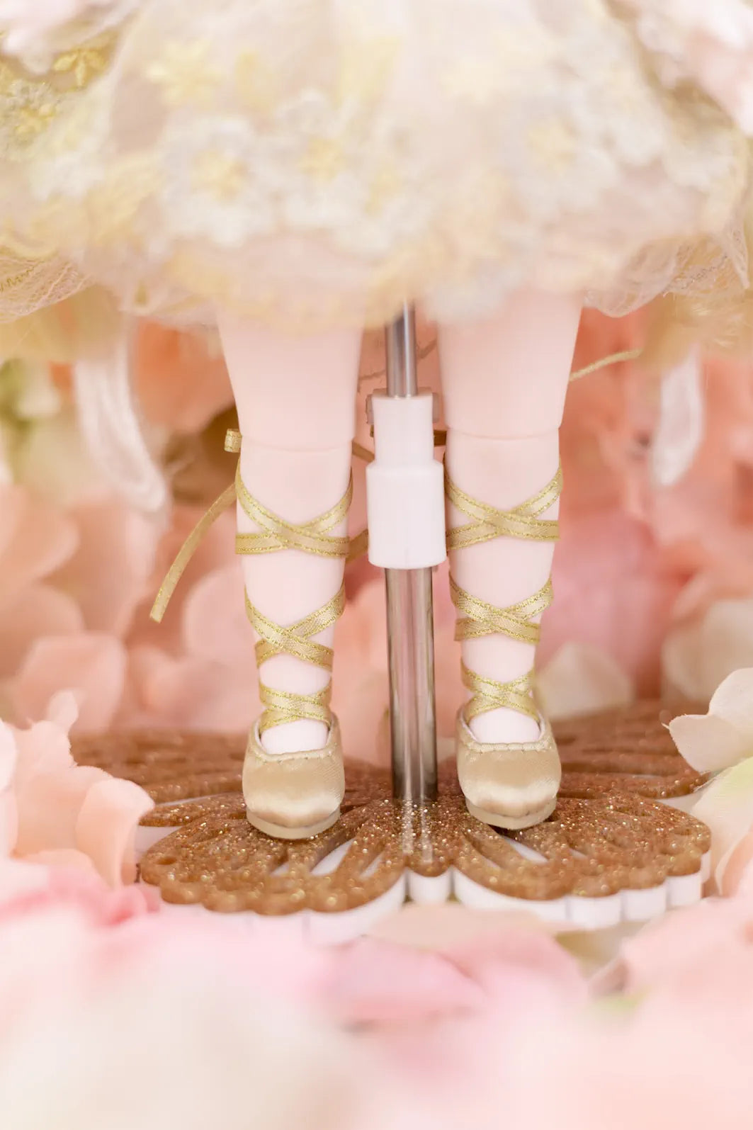 Gold color doll shoes with a decorative base on a floral background