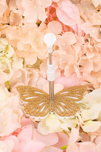 Gold butterfly-shaped doll stand on bpink and white flowers