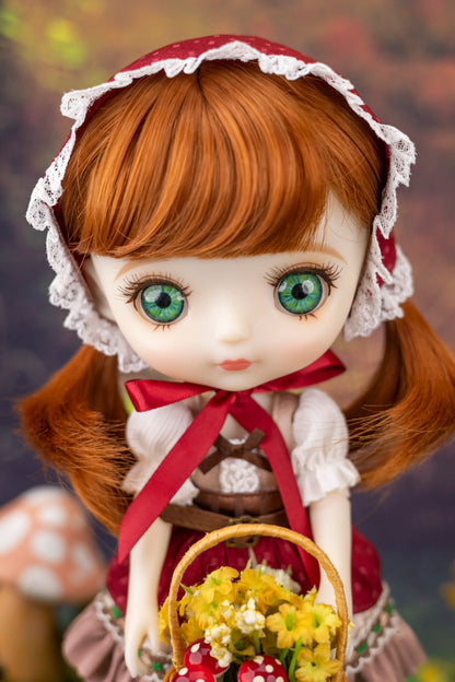 Doll with ginger hair and green eyes wearing a red bonnet and holding a basket of flowers.