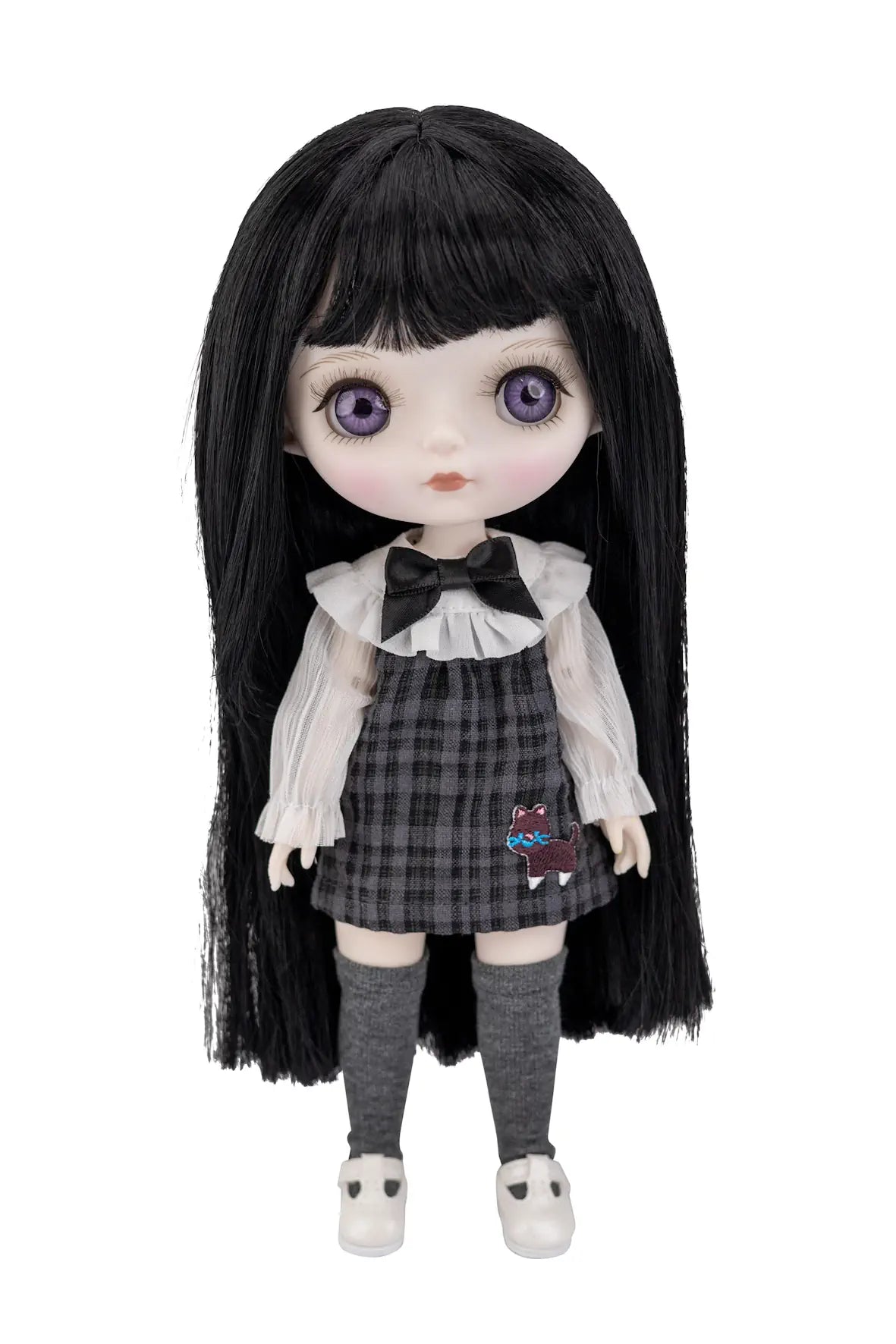 A doll with long black hair, large purple eyes, and a schoolgirl outfit consisting of a white ruffled blouse, black bow, black-and-gray plaid skirt, gray knee socks, and white shoes, shown against a plain white background.