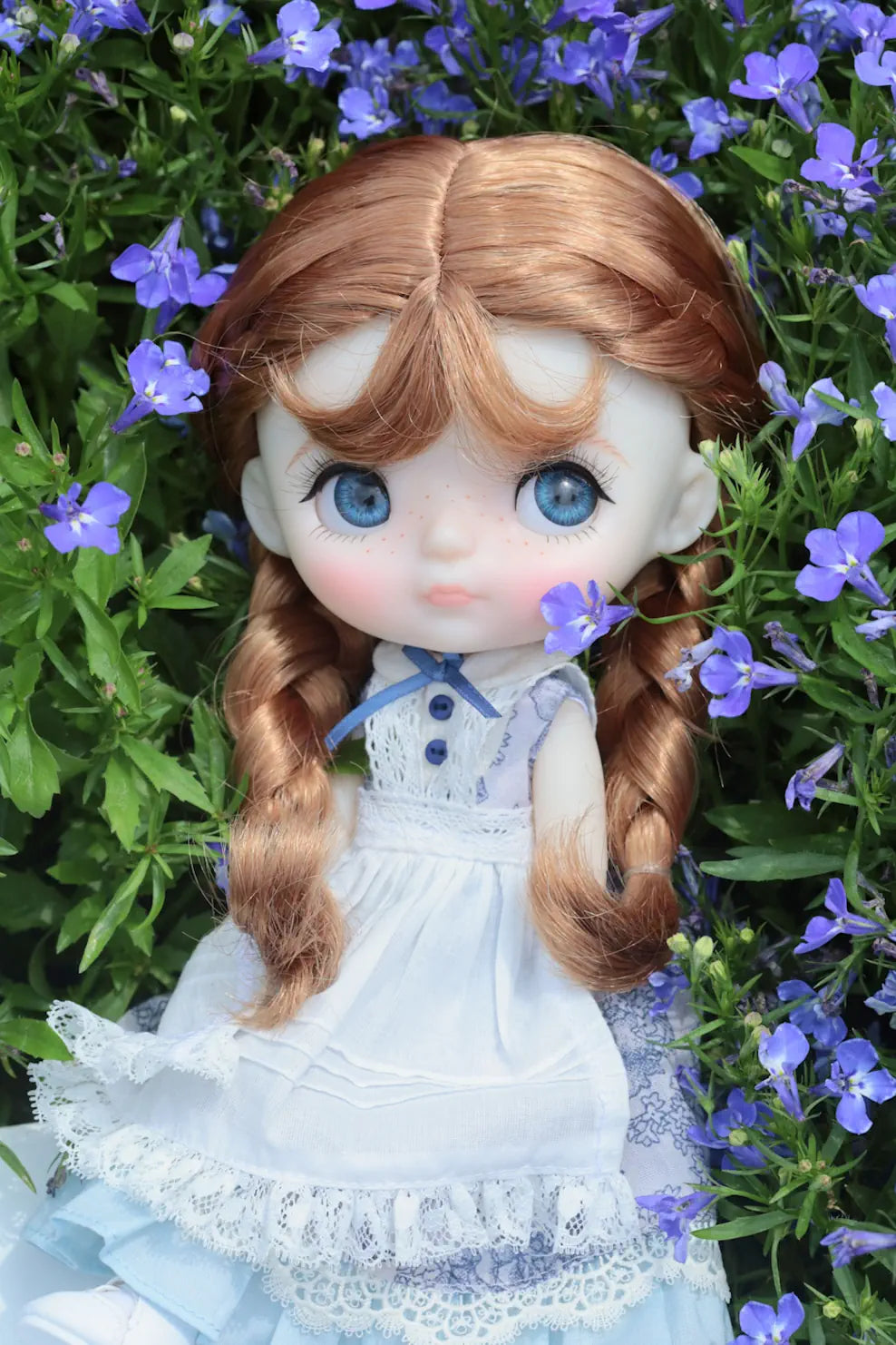 Doll with long brown hair and blue eyes surrounded by purple flowers