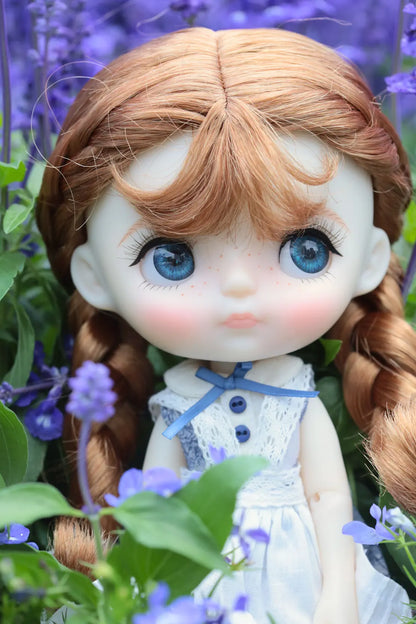 Doll with blue eyes and pigtails surrounded by purple flowers