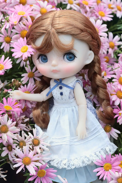 Doll with long brown hair and a white dress standing among pink flowers