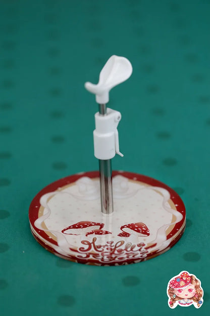 Round doll stand with a white base and red circular design on a green background