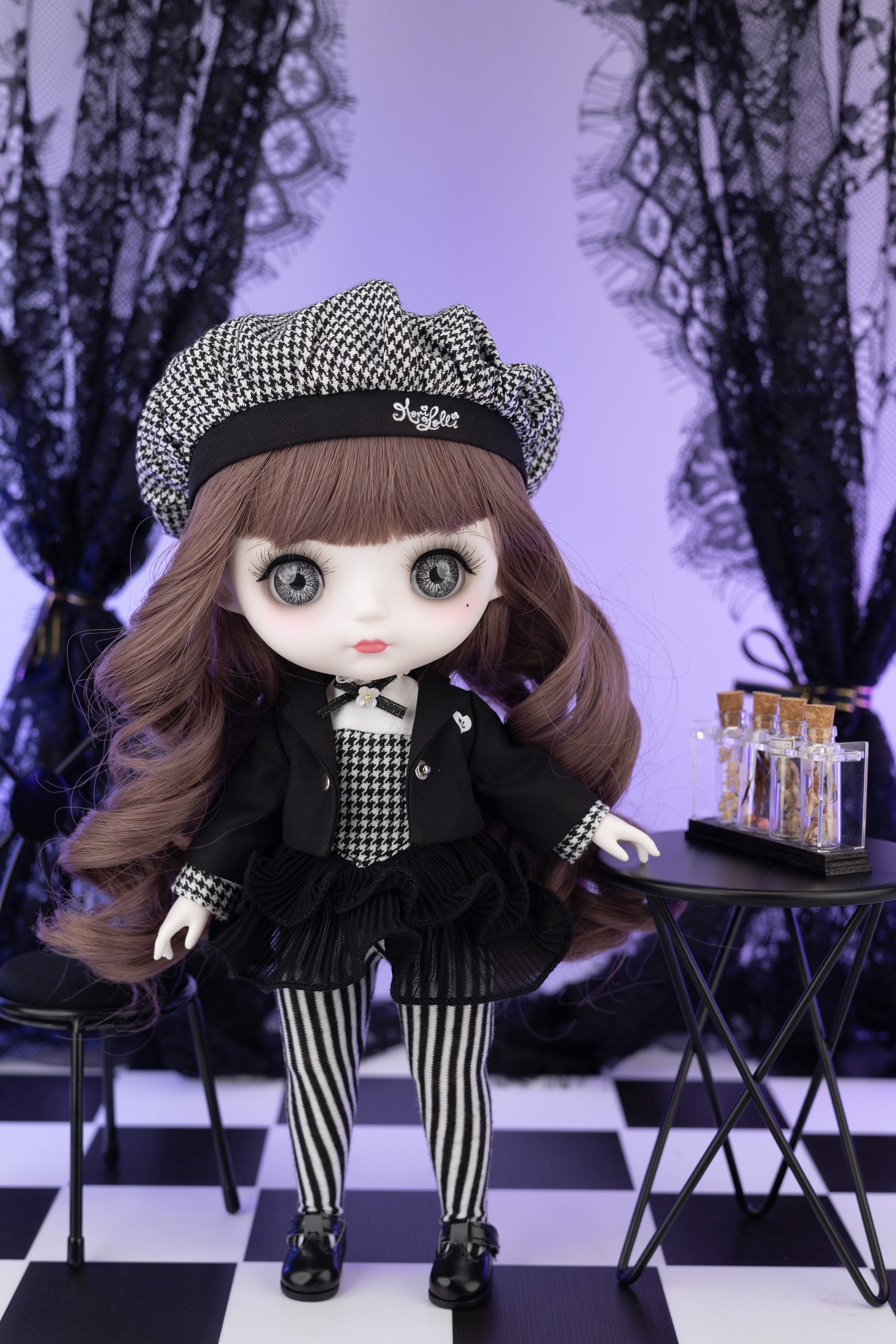 Doll in a black and white outfit with a checkered hat in a decorative setting.