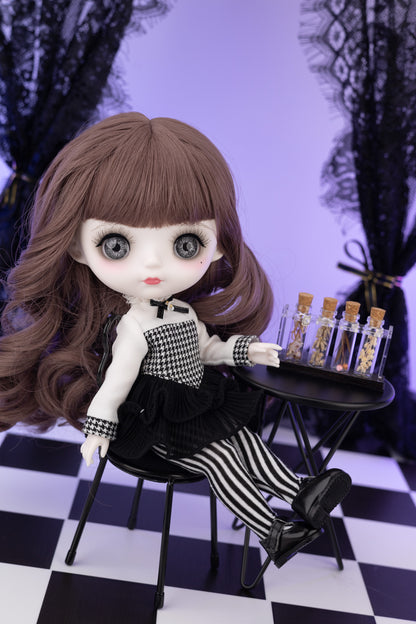 Doll with long brown hair and checkered outfit sitting on a chair with a small table in a checkered room.