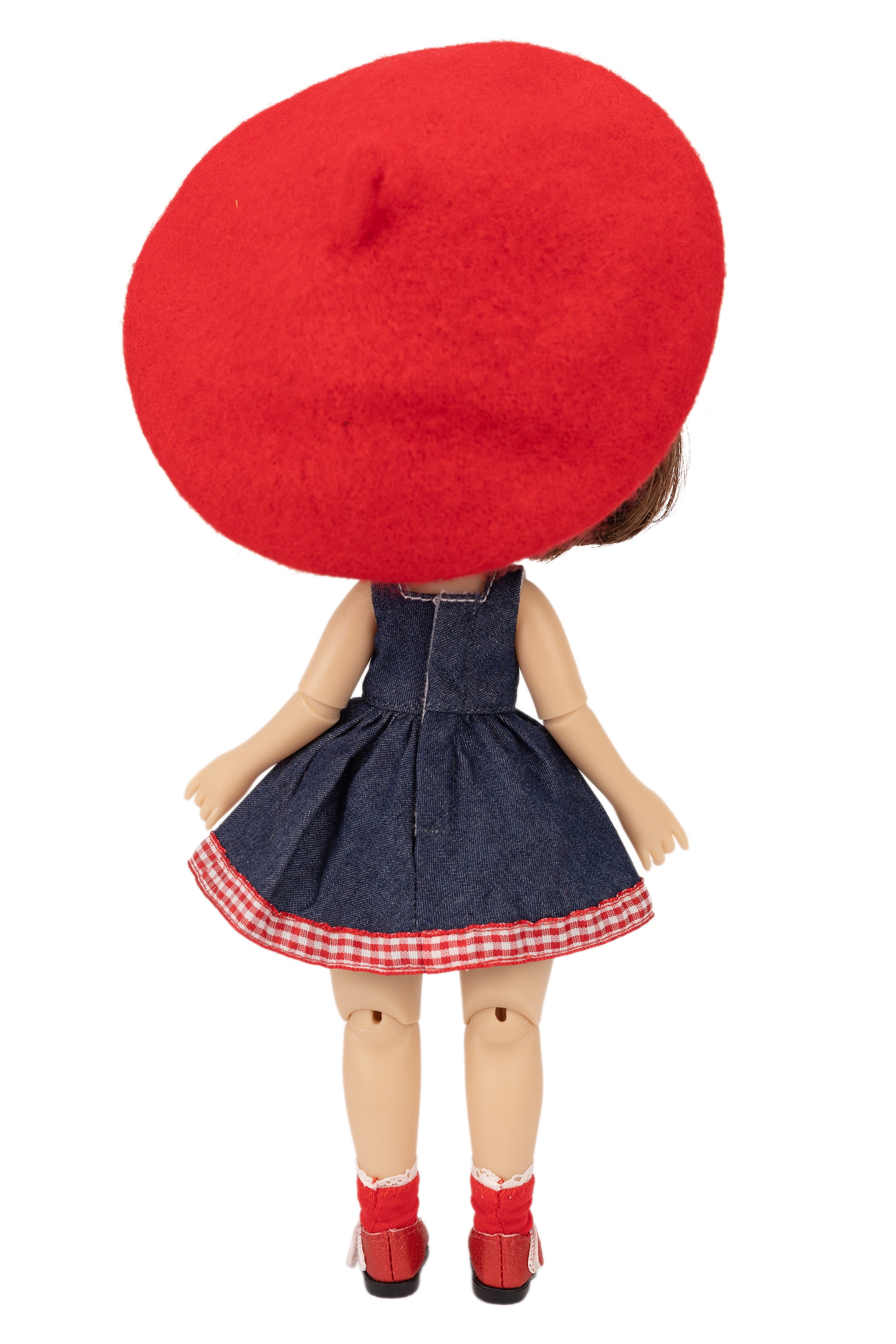 Doll wearing a red beret, denim dress with a checkered skirt, and red shoes on a white background