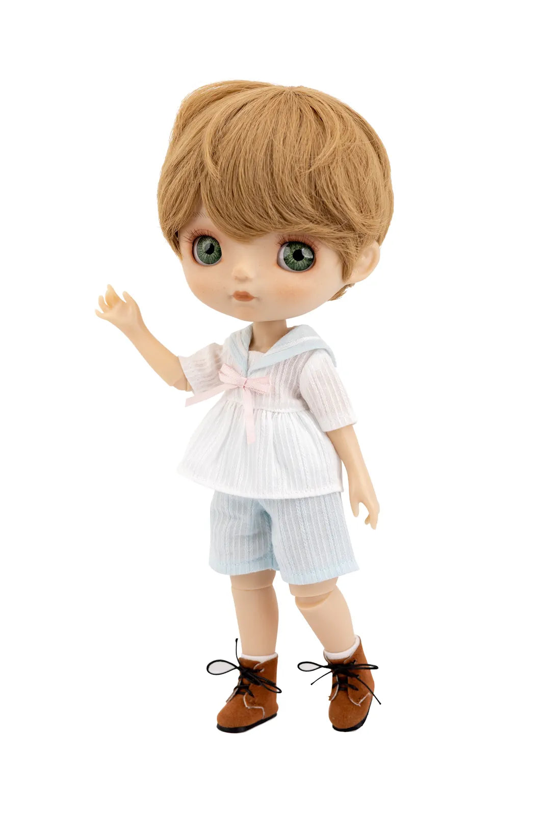 A Mori Lolli doll with large green eyes, light brown hair, and a white and light blue outfit with a pink bow, standing against a plain white background.