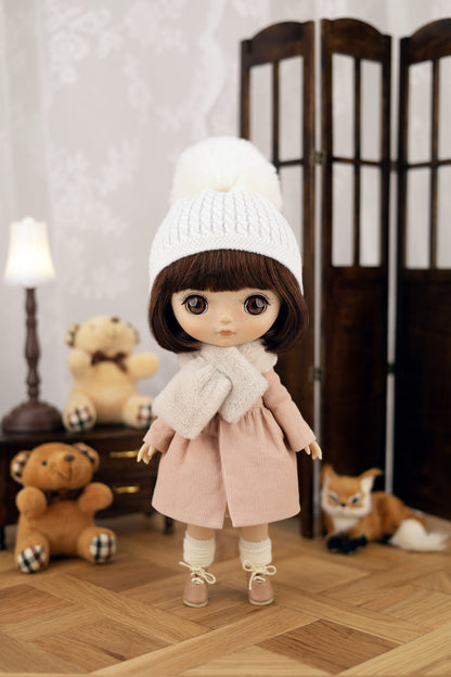 Doll wearing a white knit hat and pink coat in a room with teddy bears and a lamp.