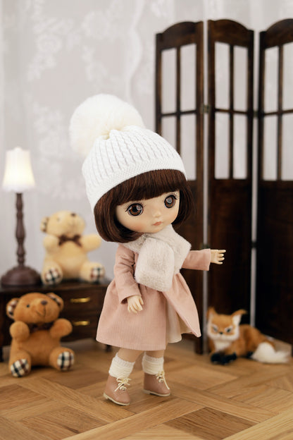 Doll wearing a white knit hat and pink coat in a room with teddy bears and a lamp.